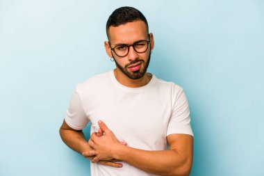 Mavi arka planda karaciğer ağrısı ve karın ağrısı çeken genç bir İspanyol..