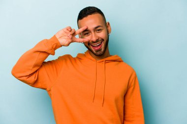 Genç İspanyol adam mavi arka planda izole edilmiş dans ediyor ve eğleniyor.