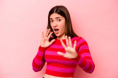 Pembe arka planda izole edilmiş genç beyaz kadın yakın bir tehlike nedeniyle şoka uğruyor.