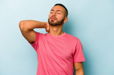 Genç İspanyol adam mavi arka planda izole edilmiş dirsek masajı yapıyor, kötü bir hareketin ardından acı çekiyor..