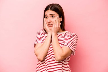 Pembe arka planda izole edilmiş genç beyaz kadın korkmuş ve korkmuş..