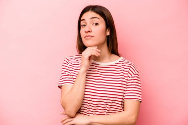 Pembe arka planda izole edilmiş genç beyaz kadın şüpheli, belirsiz, seni muayene ediyor..