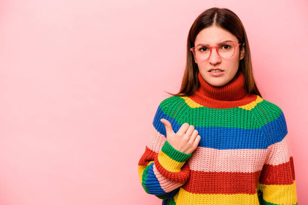 Молодая белая женщина, изолированная на розовом фоне, шокирована, указывая указательными пальцами на копировальное пространство..