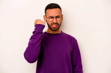 Beyaz arka planda izole edilmiş genç İspanyol adam kameraya yumruk gösteriyor, agresif yüz ifadesi..