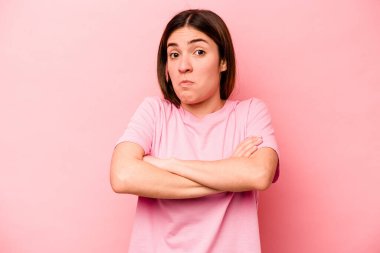 Pembe arka planda soyutlanmış beyaz bir kadın omuzlarını silkeliyor ve gözleri açık..