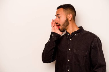 Beyaz arka planda izole edilmiş genç İspanyol bir adam gizli bir sıcak fren haberi veriyor ve yana bakıyor.