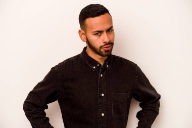 Beyaz arka planda izole edilmiş, hoşnutsuzca kaşlarını çatmış, kollarını kavuşturmuş genç bir İspanyol..