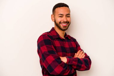 Beyaz arka planda kendini güvende hisseden, kararlılıkla kollarını kavuşturan genç İspanyol bir adam..