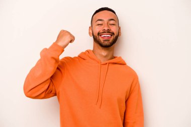 Beyaz arka planda izole edilmiş genç İspanyol bir adam zaferi, tutkuyu ve coşkuyu kutluyor, mutlu bir ifade..