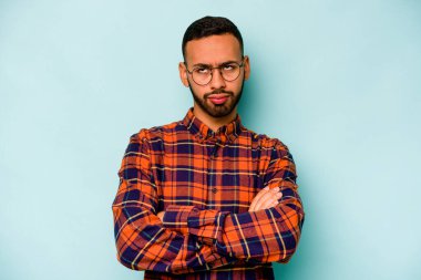 Genç İspanyol adam mavi arka planda izole edilmiş. Tekrarlanan bir görevden yorulmuş..