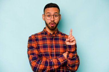 Latin kökenli genç bir adam mavi arka planda izole edilmiş. Harika bir fikri var, yaratıcılık kavramı..