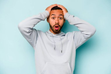 Genç İspanyol adam mavi arka planda izole edildi. Şaşırdı ve şok oldu..