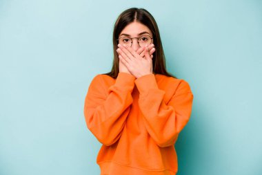 Mavi arka planda izole edilmiş beyaz bir kadın elleriyle ağzını kapatırken şok oldu..