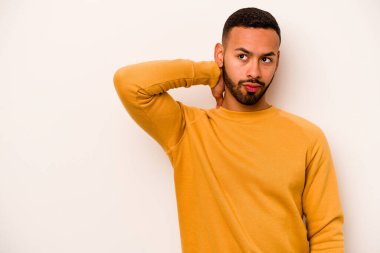 Genç İspanyol bir adam beyaz arka planda izole edilmiş kafasının arkasına dokunuyor, düşünüyor ve bir seçim yapıyor..