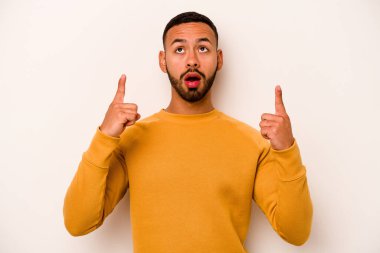 Beyaz arka planda izole edilmiş genç bir İspanyol ağzı açık bir şekilde yukarı işaret ediyor..