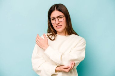 Beyaz bir kadın mavi arka planda izole edilmiş dirsek masajı yapıyor, kötü bir hareketin ardından acı çekiyor..