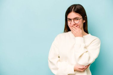 Mavi arka planda soyutlanmış genç beyaz kadın gülüyor, kaygısız, doğal duygu..