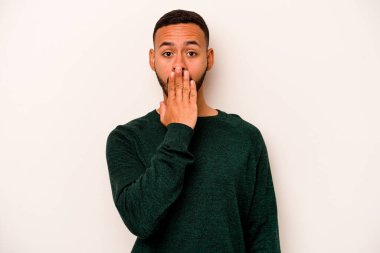 Beyaz arka planda izole edilmiş genç İspanyol adam şok olmuş, ağzı ellerle kaplanmış, yeni bir şey keşfetmeye hevesli..