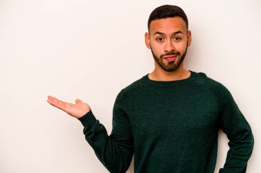 Beyaz arka planda izole edilmiş genç İspanyol bir adam bir avuç içinde fotokopi alanı ve belinde bir el daha gösteriyor..