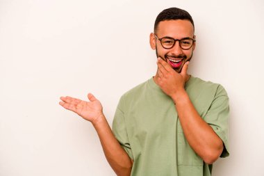 Beyaz arka planda izole edilmiş genç İspanyol bir adam avuç içinde fotokopi alanı tutuyor, el üstünde tutuyor. Şaşırmış ve mutlu..