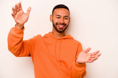 Latin kökenli genç bir adam zaferi ya da başarıyı kutlarken beyaz arka planda mahsur kaldı. Şaşırdı ve şok oldu..