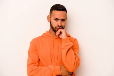 Genç İspanyol bir adam beyaz arka planda izole edilmiş düşünüyor, bakıyor, yansıtıyor, düşünüyor, bir fantezi kuruyor..