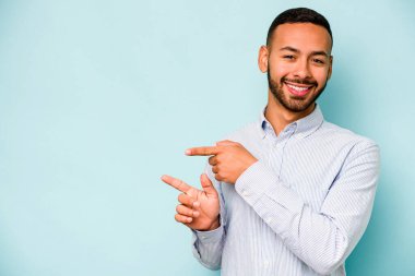 Mavi arka planda izole edilmiş genç bir İspanyol işaret parmaklarıyla işaret ederek heyecanlanıyor..