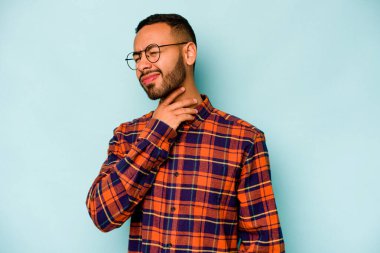 Mavi arka planda izole edilmiş genç İspanyol bir adam virüs ya da enfeksiyon yüzünden boğazında ağrı hissediyor..