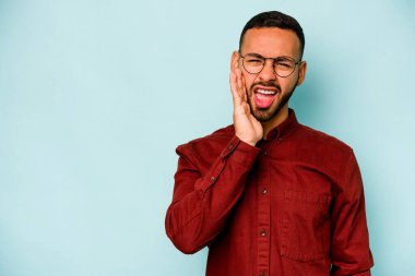 Mavi arka planda izole edilmiş genç bir İspanyol yüksek sesle bağırıyor, gözleri açık ve elleri gergin tutuyor..
