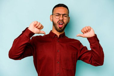 Mavi arka planda izole edilmiş genç bir İspanyol gururlu ve kendinden emin hissediyor, örnek olarak..