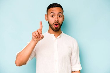 Mavi arka planda izole edilmiş genç bir İspanyol ağzı açık bir şekilde üst tarafı işaret ediyor..