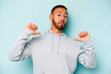Mavi arka planda izole edilmiş genç bir İspanyol gururlu ve kendinden emin hissediyor, örnek olarak..