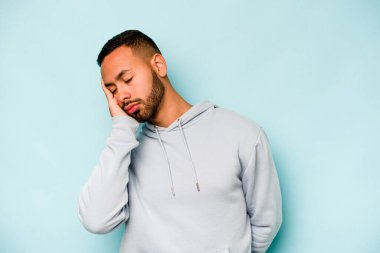 Mavi arka planda izole edilmiş genç bir İspanyol. Sıkılmış, yorgun ve dinlenmeye ihtiyacı var..