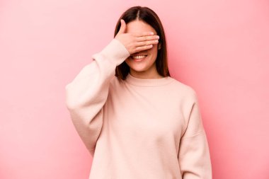 Pembe arka planda soyutlanmış beyaz bir kadın elleriyle gözlerini kapatıyor, büyük bir gülümsemeyle bir sürpriz bekliyor..