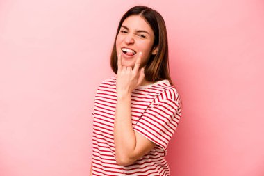 Pembe arka planda izole edilmiş genç beyaz kadın parmaklarıyla taş hareketi gösteriyor.