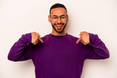 Beyaz arka planda izole edilmiş genç İspanyol adam parmağını göstererek şaşırdı, geniş bir gülümsemeyle..