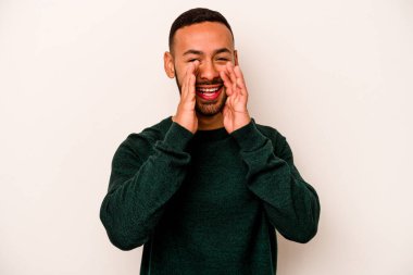 Latin kökenli genç bir adam beyaz arka planda izole edilmiş. Dedikodu yapıyor, bir şeyleri bildiriyor..
