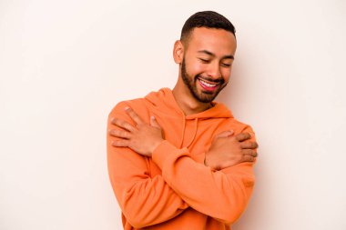 Beyaz arka planda yaşayan genç İspanyol adam gülüyor ve eğleniyor..