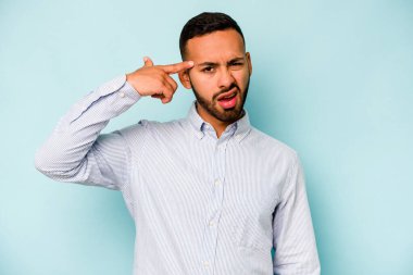Mavi arka planda izole edilmiş genç İspanyol adam işaret parmağıyla bir hayal kırıklığı gösteriyor..