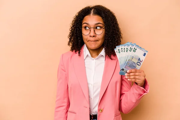 Mladá Afroameričanka Která Drží Bankovky Izolované Béžovém Pozadí Zmatená Pochybná — Stock fotografie