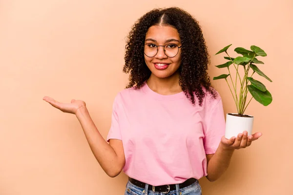 Young African American Woman Holding Plant Isolated Beige Background Showing — 스톡 사진