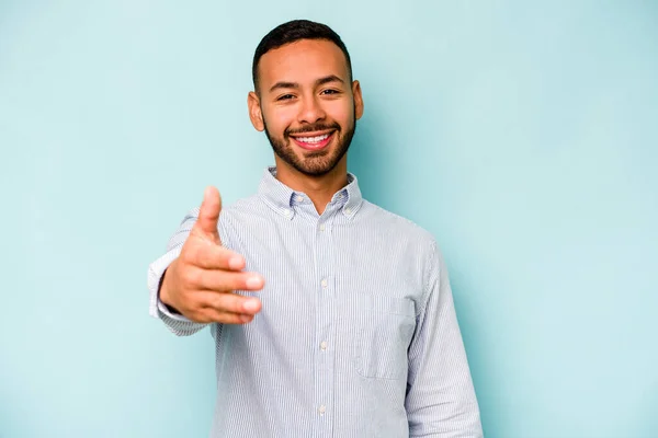 Jonge Spaanse Man Geïsoleerd Blauwe Achtergrond Stretching Hand Camera Groet — Stockfoto