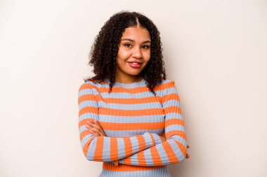 Beyaz arka planda izole edilmiş genç bir Afrikalı Amerikalı kadın. Kendini güvende hissediyor, kararlılıkla kollarını kavuşturuyor..