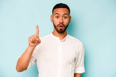 Latin kökenli genç bir adam mavi arka planda izole edilmiş. Harika bir fikri var, yaratıcılık kavramı..