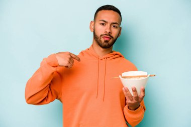 Mavi arka planda izole edilmiş erişte yiyen genç İspanyol kadın gururlu ve kendinden emin hissediyor, örnek olarak..