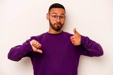 Beyaz arka planda izole edilmiş genç bir İspanyol, baş parmağını kaldırıyor, zor bir seçim.