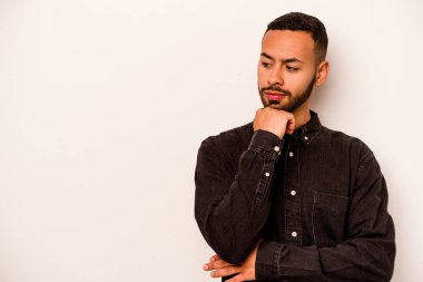 Beyaz arka planda izole edilmiş genç bir İspanyol şüpheli ve şüpheci bir ifadeyle yana bakıyor..