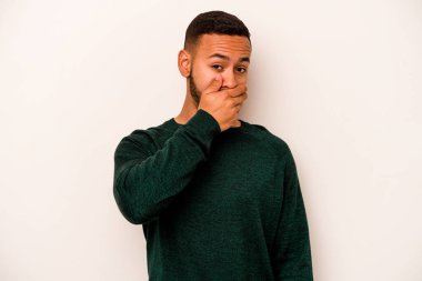 Beyaz arka planda izole edilmiş genç İspanyol adam elleri endişeli bir şekilde ağzı örtüyor..