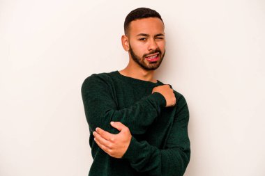 Genç İspanyol bir adam beyaz arka planda izole edilmiş, dirsek masajı yapıyor, kötü bir hareketin ardından acı çekiyor..