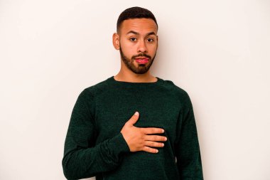 Beyaz arka planda izole edilmiş genç İspanyol adam karnına dokunuyor, nazikçe gülümsüyor, yemek yiyor ve tatmin oluyor..